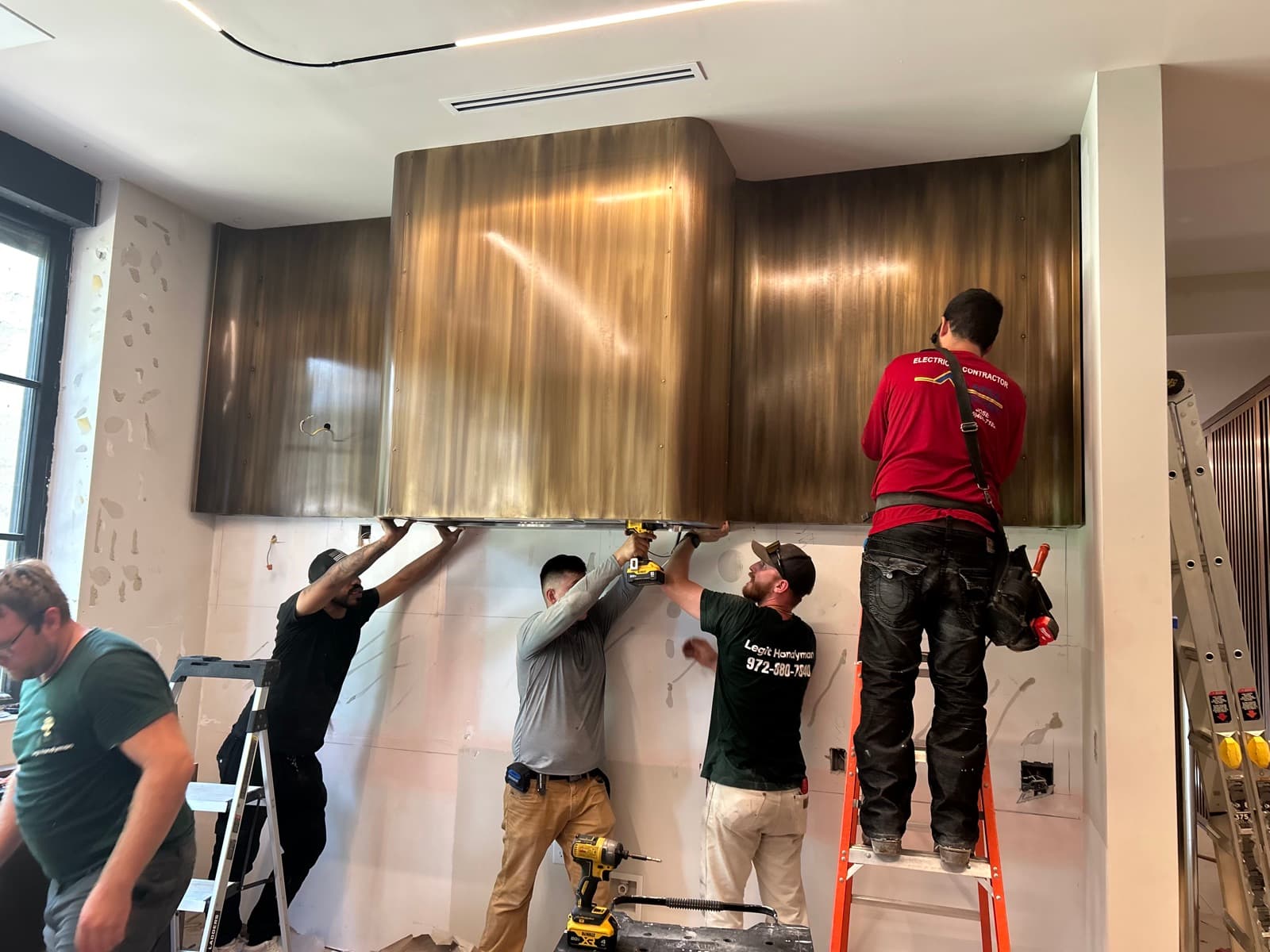 Team installing large brass range hood